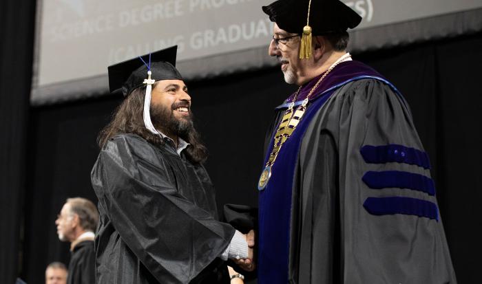 Dr. Luis Pedraja congratulating a student Dr. Luis Pedraja congratulating a student