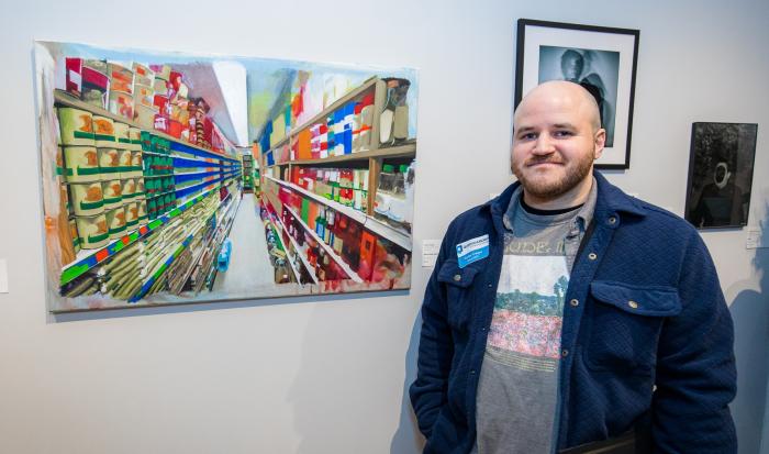 Carlos Crespo with his painting "Silver, Sword, and Stone". Photo by Nathan Fiske.