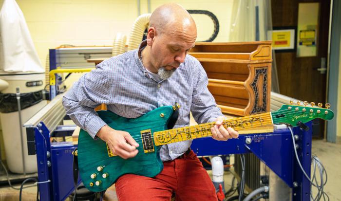 Professor of Music Jose Castillo playing the guitar that Marc Bolduc created for his manufacturing capstone project