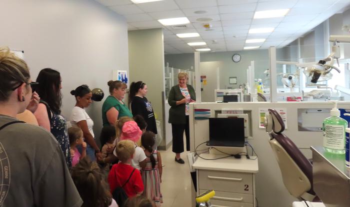 Dental Clinic Operations and Facilities Manager Sheryl Ficorilli (right) shows off dental equipment to the children.