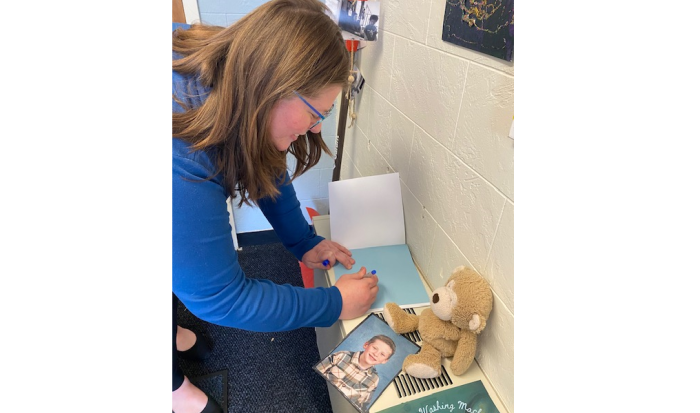 Enrollment Counselor Caitlin Bogue signs a copy of her book "Everett's Washing Machine" for the Children’s School: Early Childhood Education Lab School Enrollment Counselor Caitlin Bogue signs a copy of her book "Everett's Washing Machine" for the Children’s School: Early Childhood Education Lab School