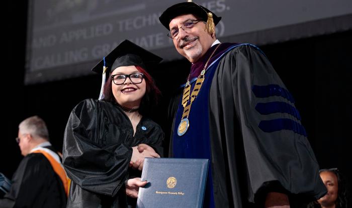 QCC President Dr. Luis Pedraja shares in the joy of receiving a diploma.