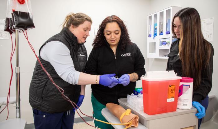 Associate Professor of Medical Assisting Cheryl DeCoff (left) guiding students in the medical assistant apprenticeship degree program.