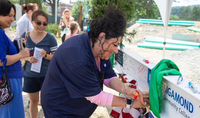 Director of Athletics & Fitness Center Lisa Gurnick signs the beam.