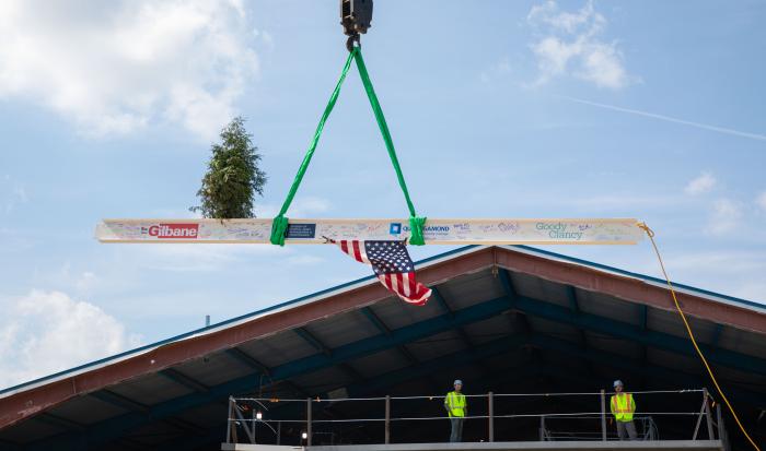The ceremonial beam raising includes a tree that symbolizes resilience.