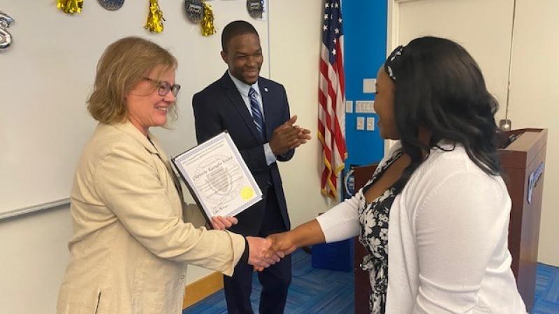 A student receiving their pre-apprentice certificate from Laura Lee and Kwesi Foster