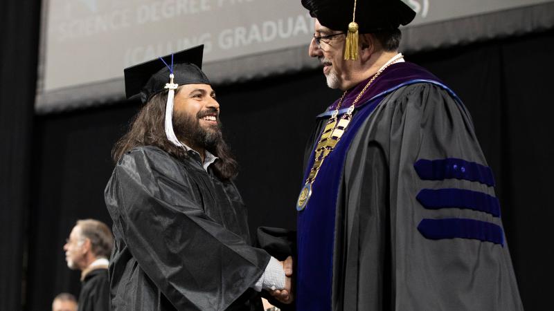 Dr. Luis Pedraja congratulating a student