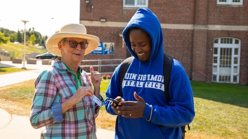 A volunteer from Third Act Massachusetts helps a QCC student register to phone with their phone.