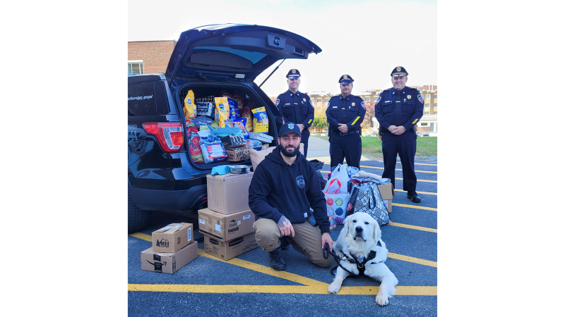(front) Campus Police Officer Nick Yacuzzi with Community Resource Dog Siggy and (back, from left) Deputy Chief of Police Operations Mike Vigeant, Deputy Chief of Administration Reynaldo Rodriguez and Chief of Police Stephen DiGiovanni with a truckload of supplies for pets of hurricane victims.