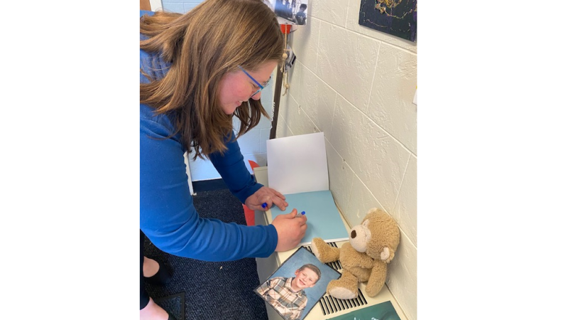Enrollment Counselor Caitlin Bogue signs a copy of her book "Everett's Washing Machine" for the Children’s School: Early Childhood Education Lab School