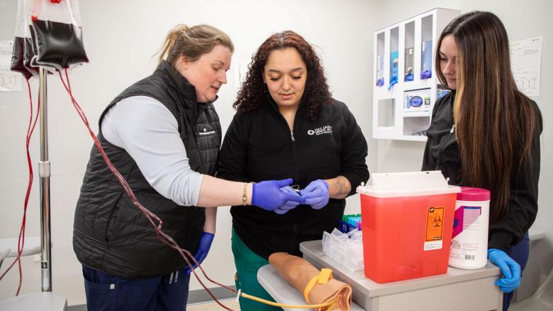 Associate Professor of Medical Assisting Cheryl DeCoff (left) guiding students in the medical assistant apprenticeship degree program.