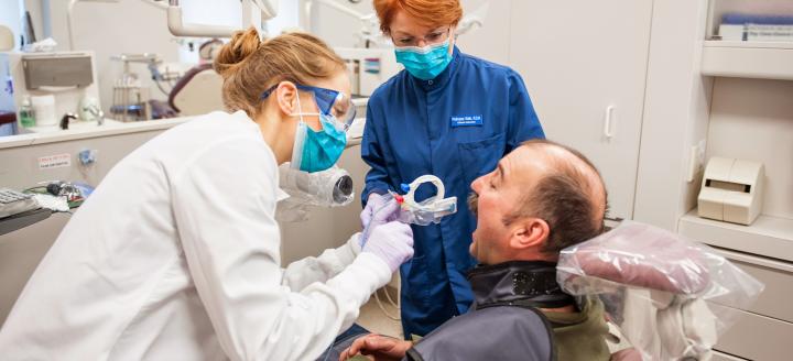 A student and instructor attend to a patient in the dental lab