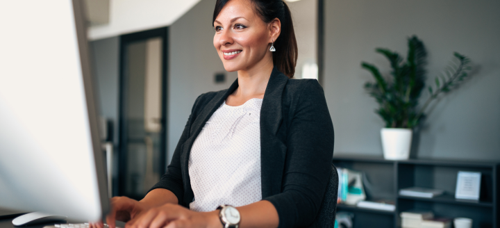 A woman types at a computer desk