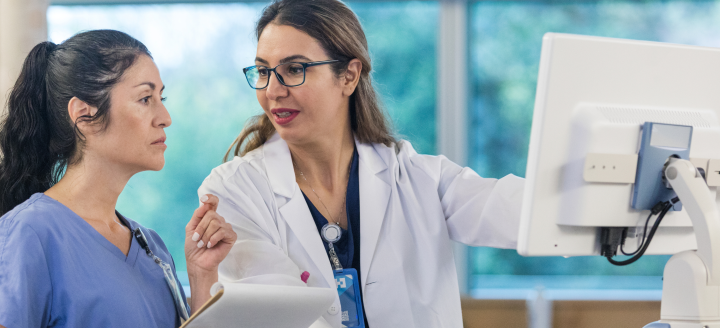 A lab tech shows another woman data from a screen