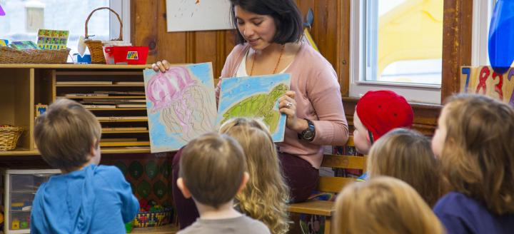 A teacher sits in front of a class of young children