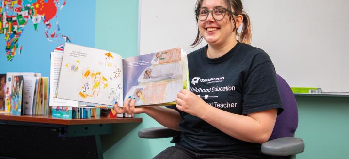 A QCC student reads a book to the class