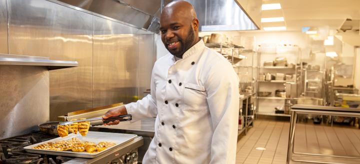 A chef works at a grill in an industrial kitchen