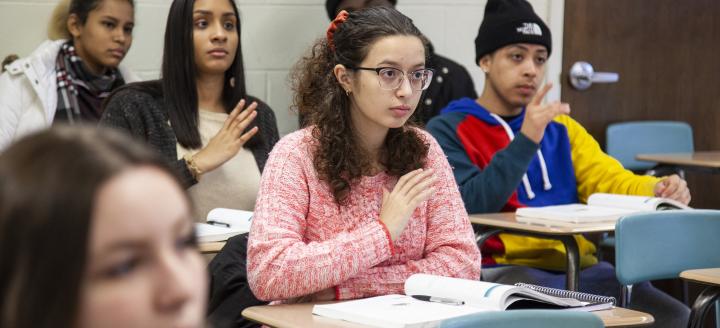 A class full of students practices sign language.