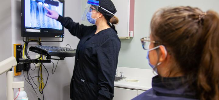 A lab tech shows a tooth x-ray to a patient