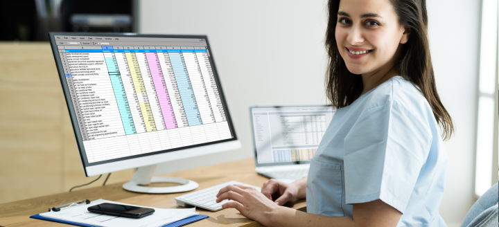 A woman in scrubs works on a spreadsheet