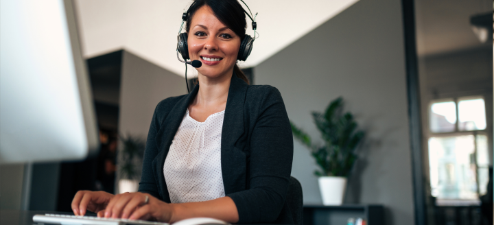 A woman with a headset works on a computer