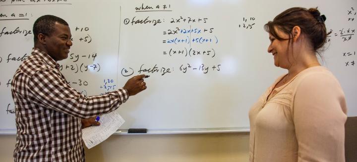 An instructor points out a math equation on a whiteboard