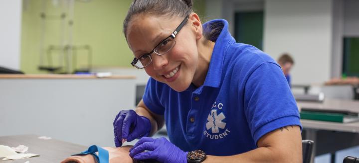 A woman works with the model of an arm to draw blood