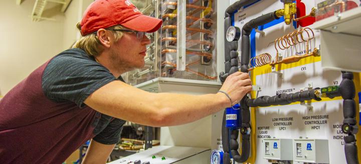 A student configures valves on a practice board in a lab