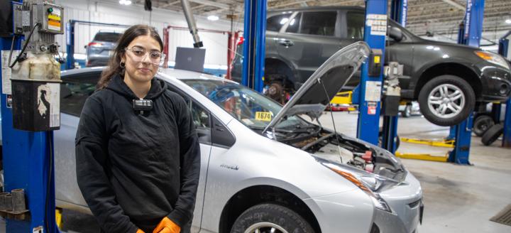 A QCC student works on cars in a garage.
