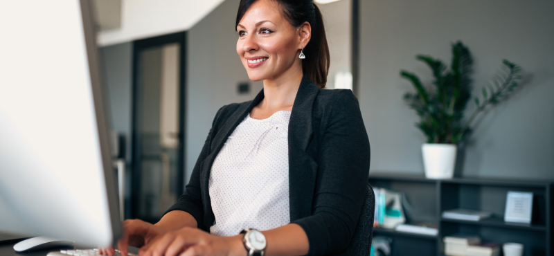 A woman types at a computer desk