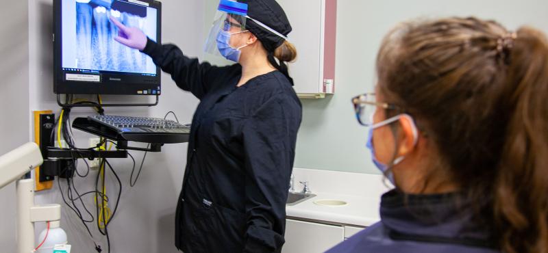 A lab tech shows a tooth x-ray to a patient