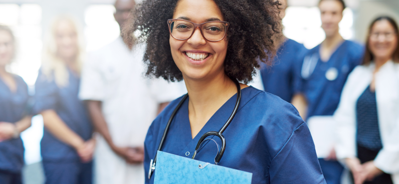 A woman in scrubs holds a folder