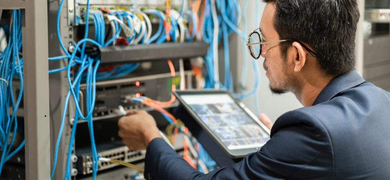 A man configures wires on the back of a server tower