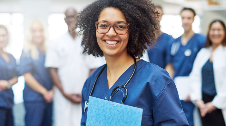 A woman in scrubs holds a folder